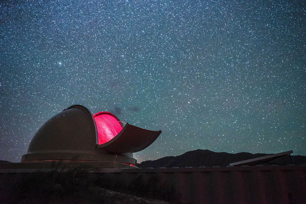 Night sky filled with stars with open hatch on observatory