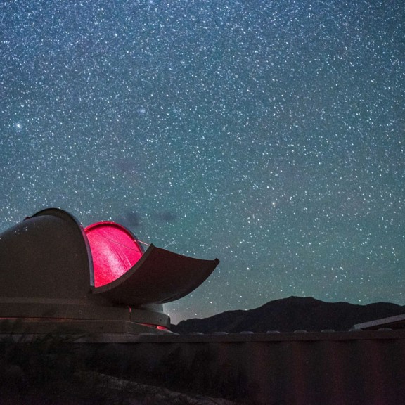 Night sky filled with stars with open hatch on observatory