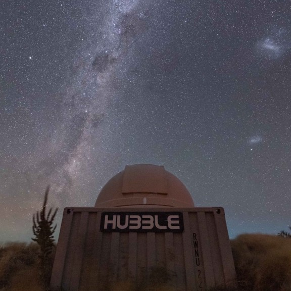Milky way shown in the night sky behind hubble observatory