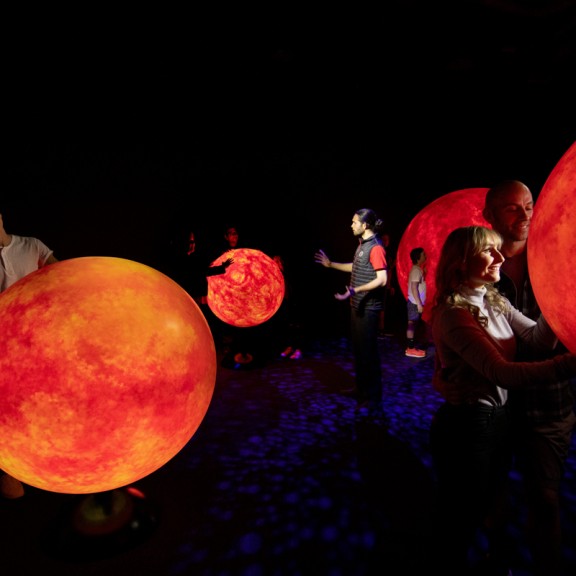 Room filled with people and 3D red glowing orbs 