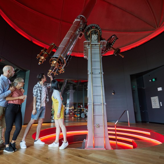 Family of four looking through brashear telescope inside