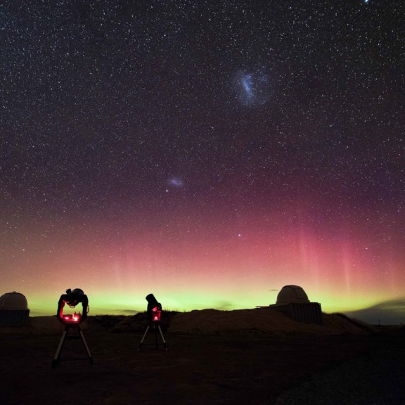 Aurora in the night sky with telescopes set in the foreground