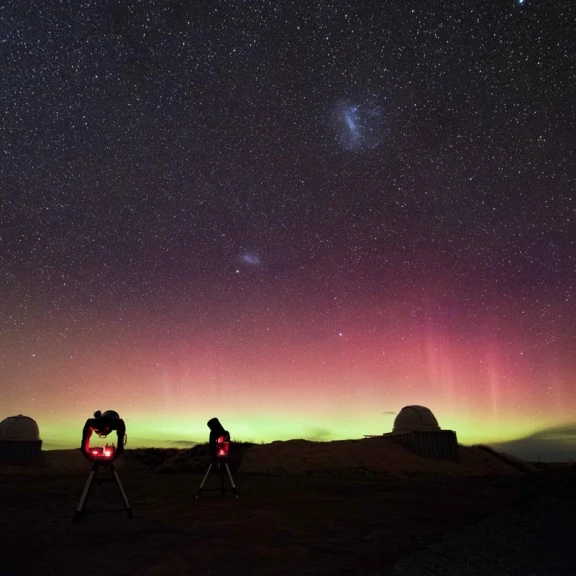 Aurora in the night sky with telescopes set in the foreground