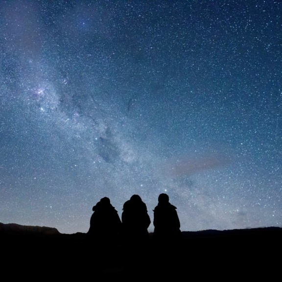 Silhouette of three people from behind looking at the milky way